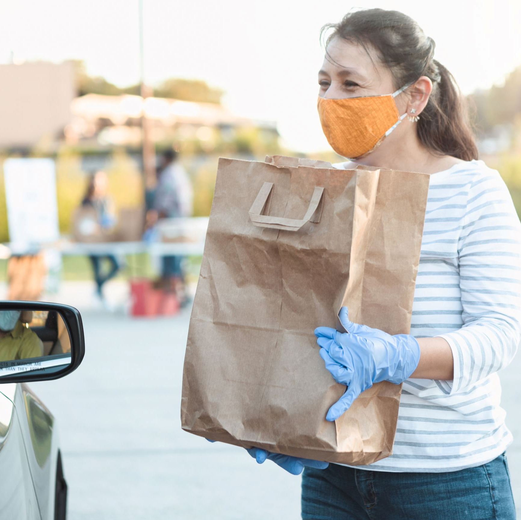 A woman shares a bag of groceries with a passing car.