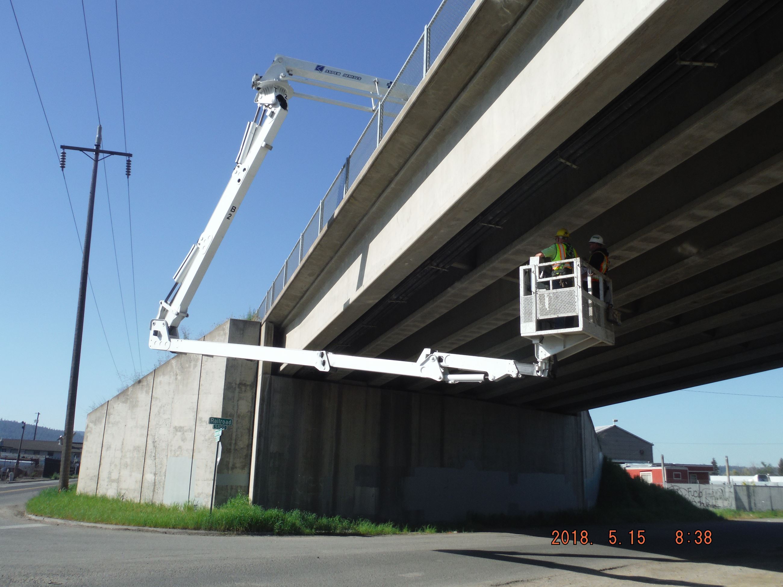 Two engineers inspect the underside of a highway underpass.