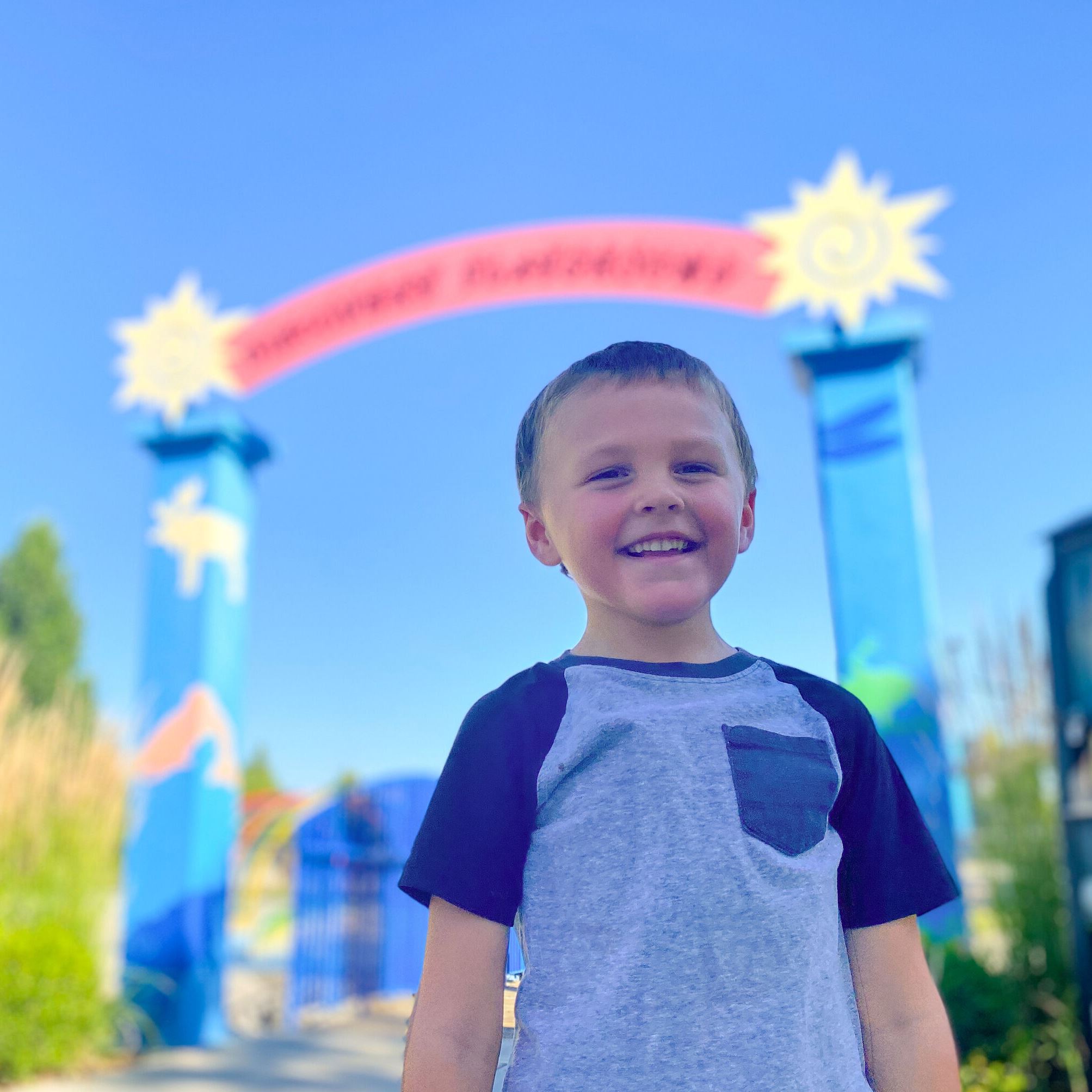A child stands under the entry sign at Discovery Playground.