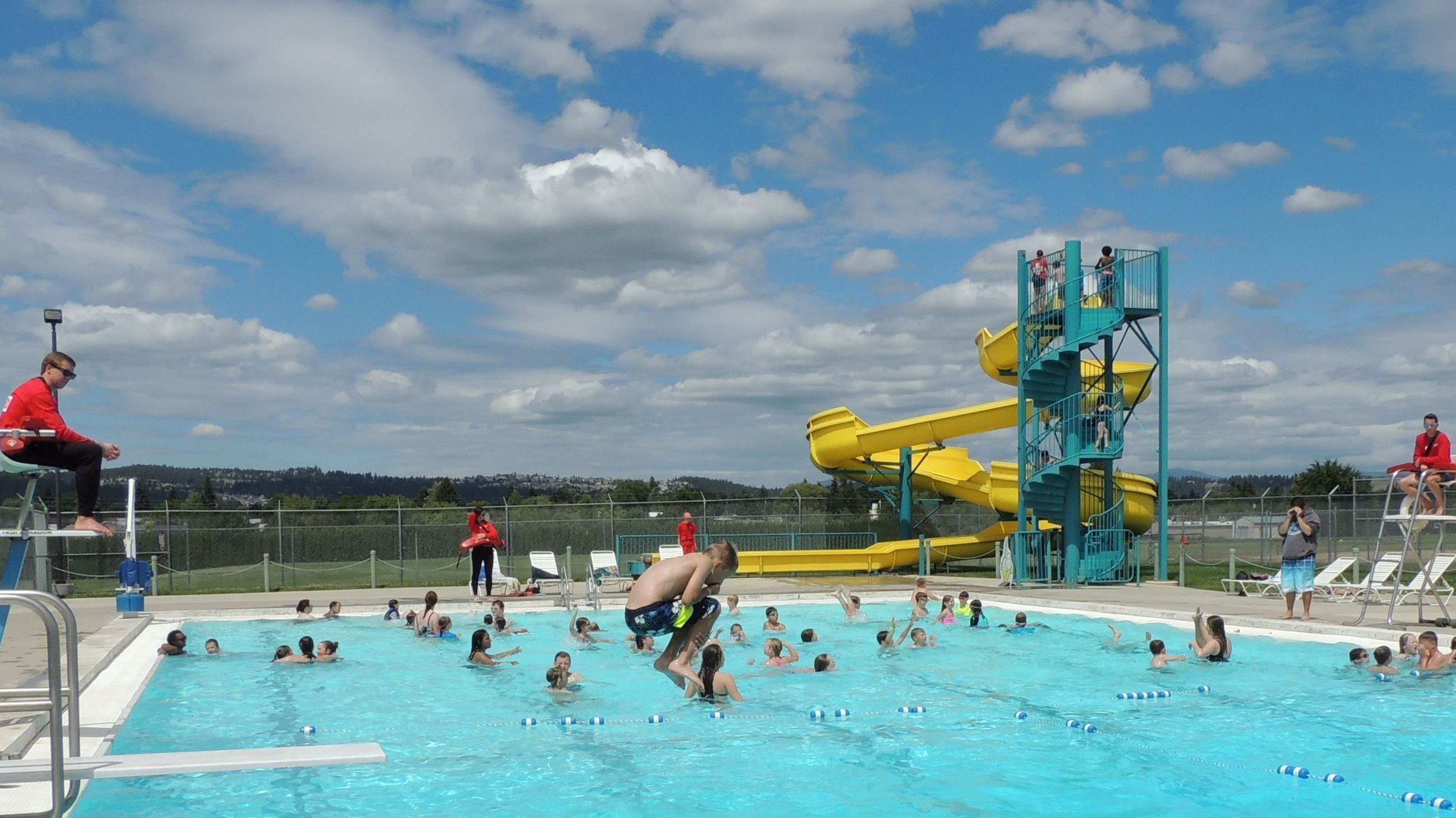 A boy mid-jump from the diving board in to Park Road Pool